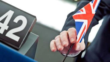 En ledamot i Europaparlamentet ställer fram den brittiska flaggan i plenum.